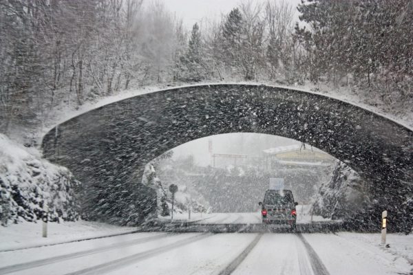 Car with winter tires driving through snow storm in alberta